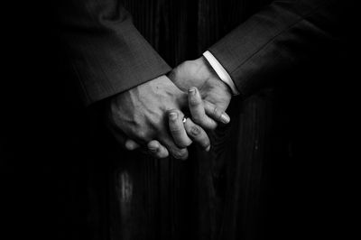 Close-up of gay men holding hands in dark