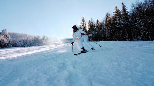 Woman skiing on snow covered field against clear sky