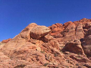 Low angle view of rock formation against clear blue sky