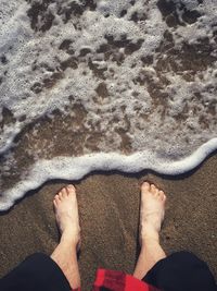 Low section of man standing at beach