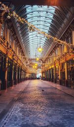 Illuminated walkway amidst buildings in city