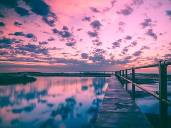 Pier over lake against sky during sunset