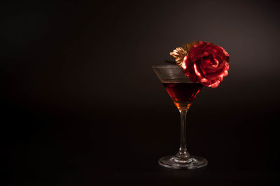 Close-up of red rose in glass against black background