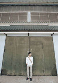 Full length portrait of man standing against building