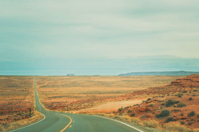 Road amidst field against sky