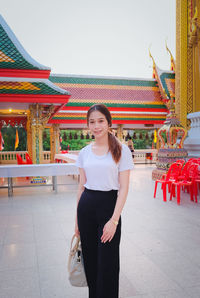 Portrait of smiling young woman standing against temple