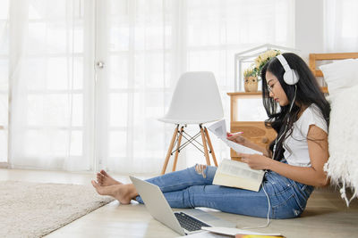 Woman using phone while sitting on floor