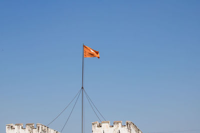 Low angle view of flags against clear blue sky