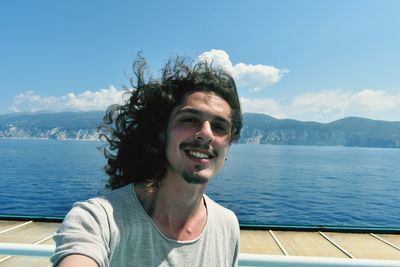 Portrait of smiling young man against sea against sky