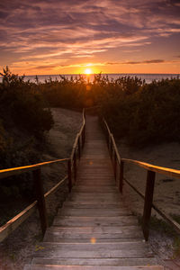 Wooden bridge against sky during sunset