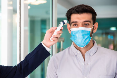 Businessman wearing mask checking temperature at office