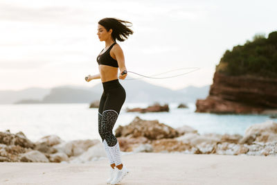 Full length of young woman exercising on beach