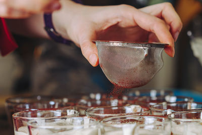 Cropped hand of woman holding sieve making sweet food