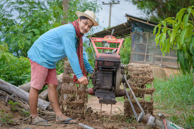 Full length portrait of farmer using agricultural machinery