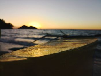 Close-up of wood at beach against sky during sunset