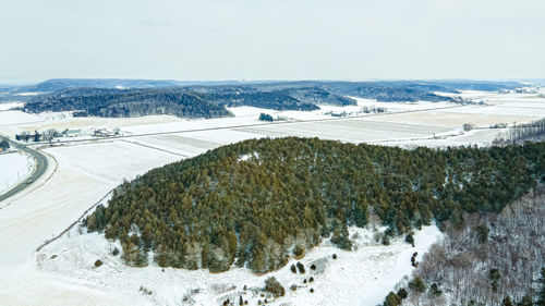 Snow covers the hills and fields with farm fields between the slopes.