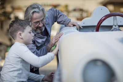Senior man and boy examining old car together