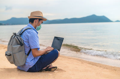 Man using mobile phone while sitting on beach