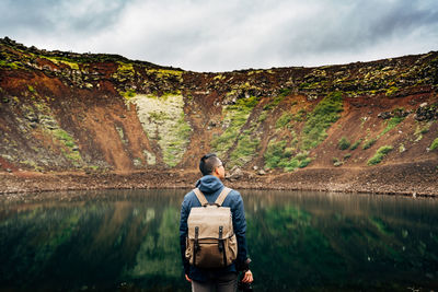 Rear view of man standing by lake