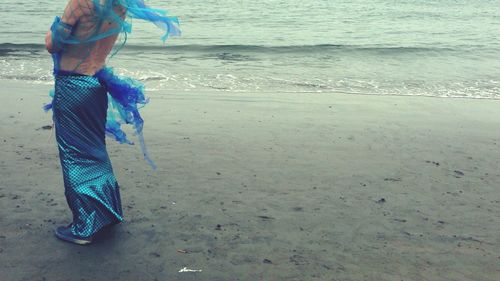 Low section of man standing on beach