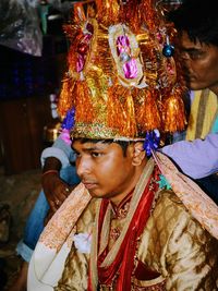 Thoughtful bridegroom wearing headdress during wedding ceremony