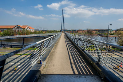 Railroad tracks by bridge against sky