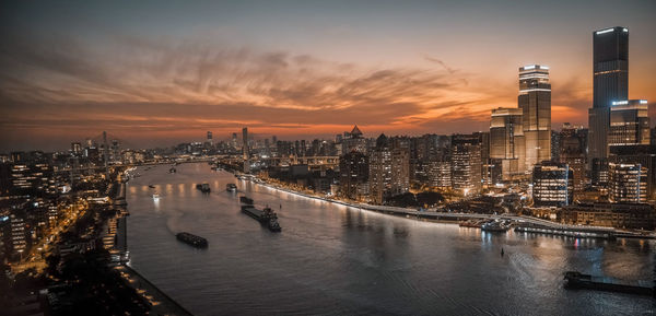 Illuminated buildings in city at sunset