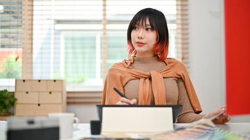 Portrait of young woman using laptop while sitting on table