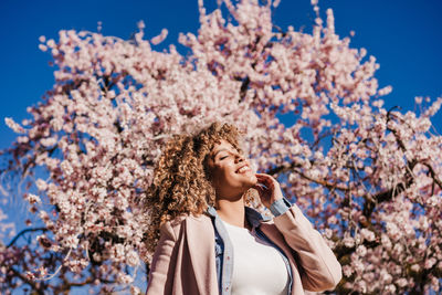 Portrait of young woman standing against trees