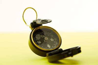 Close-up of navigational compass against yellow background