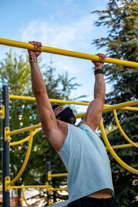 Athletic male exercising chin-ups in playground