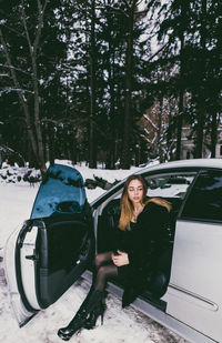 Full length of young woman sitting on car seat during winter