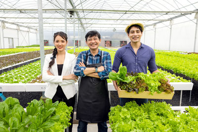 Portrait of a smiling young woman standing in greenhouse