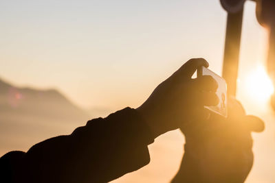 Silhouette person photographing at sunset