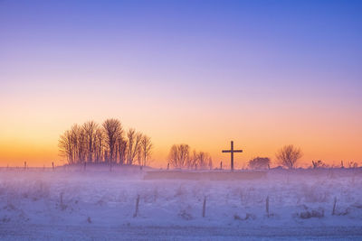 Snow covered field against sky during sunset