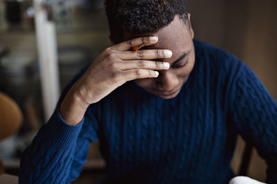 Stressed teenage boy with head in hand studying at home