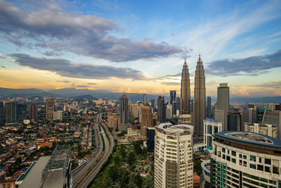 Petronas towers amidst cityscape against sky during sunrise