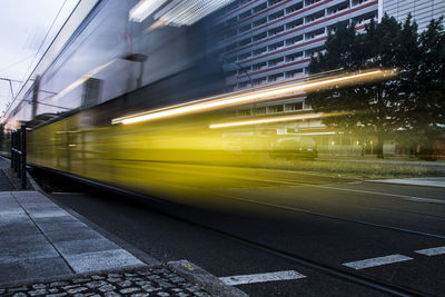 Blurred motion of train on road in city against sky