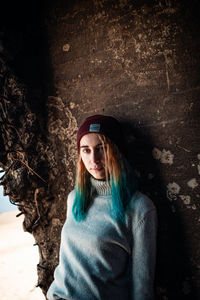 Portrait of woman wearing knit hat standing against wall