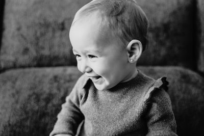 Smiling baby girl looking away while sitting on sofa