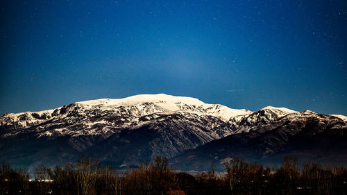 Scenic view of snowcapped mountains against blue sky at night