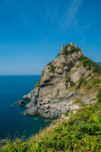 Scenic view of rocks by sea against blue sky