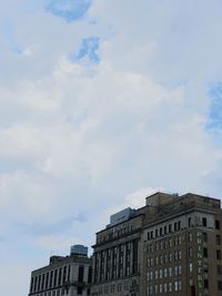 Low angle view of buildings against cloudy sky