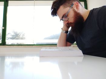 Young man looking away while sitting on table