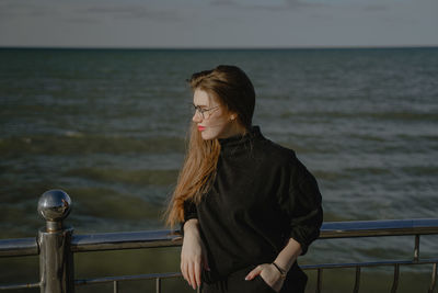Side view of young woman standing at beach