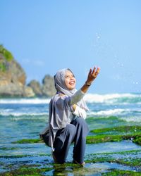 Full length of happy young woman standing on beach