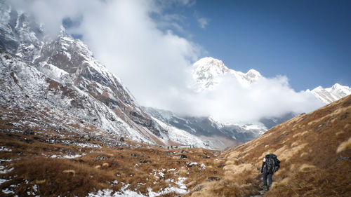 Rear view of backpack man hiking on mountain during winter