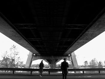 Low angle view of people standing under bridge