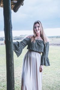 Portrait of smiling young woman standing on field