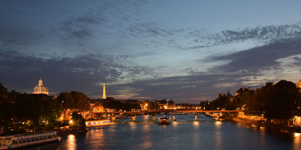 Illuminated bridge over river against sky at dusk